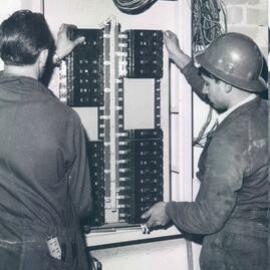 Melbourne Project - December 1961-September 1966 - Electricians placing electrical sub-board in position - 3rd floor - 20 May 1965